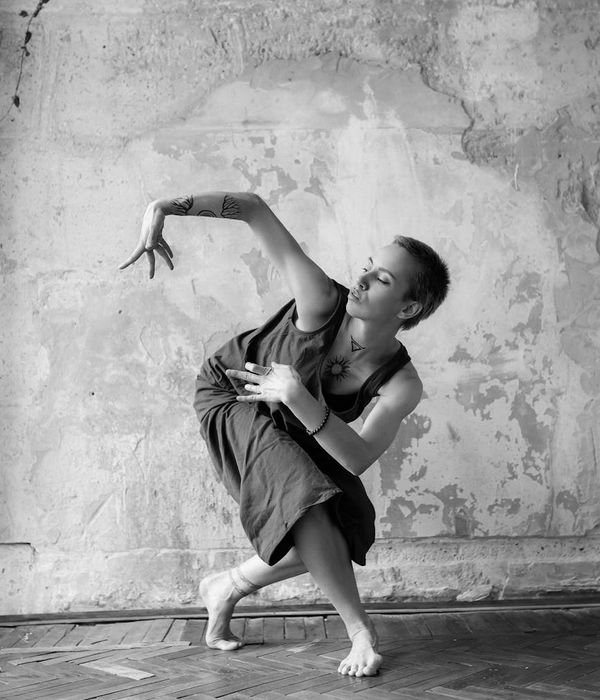 Woman in a fluid motion pose against a pale grainy background.